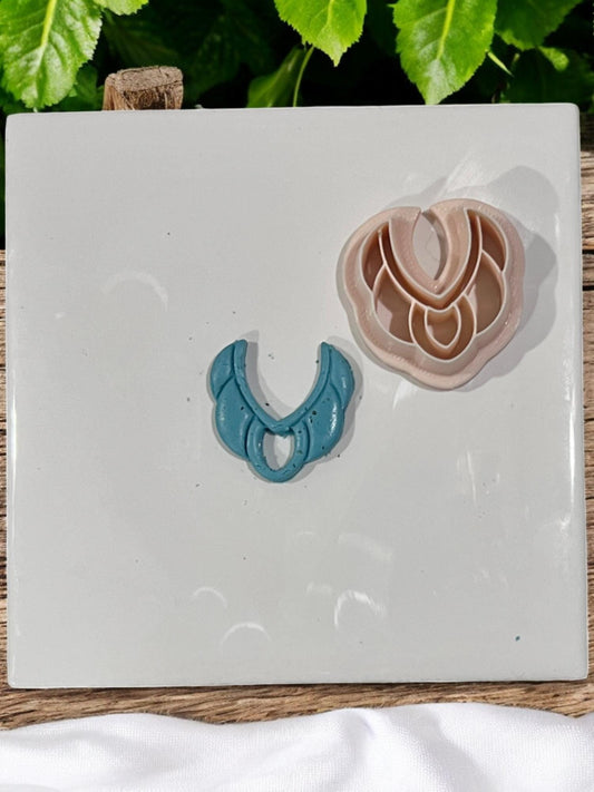 Finished blue clay design next to layered beige cutter set