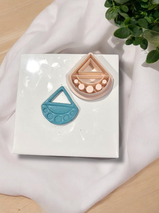 Side-by-side view of nude polymer clay cutter and blue clay cutout on white tile