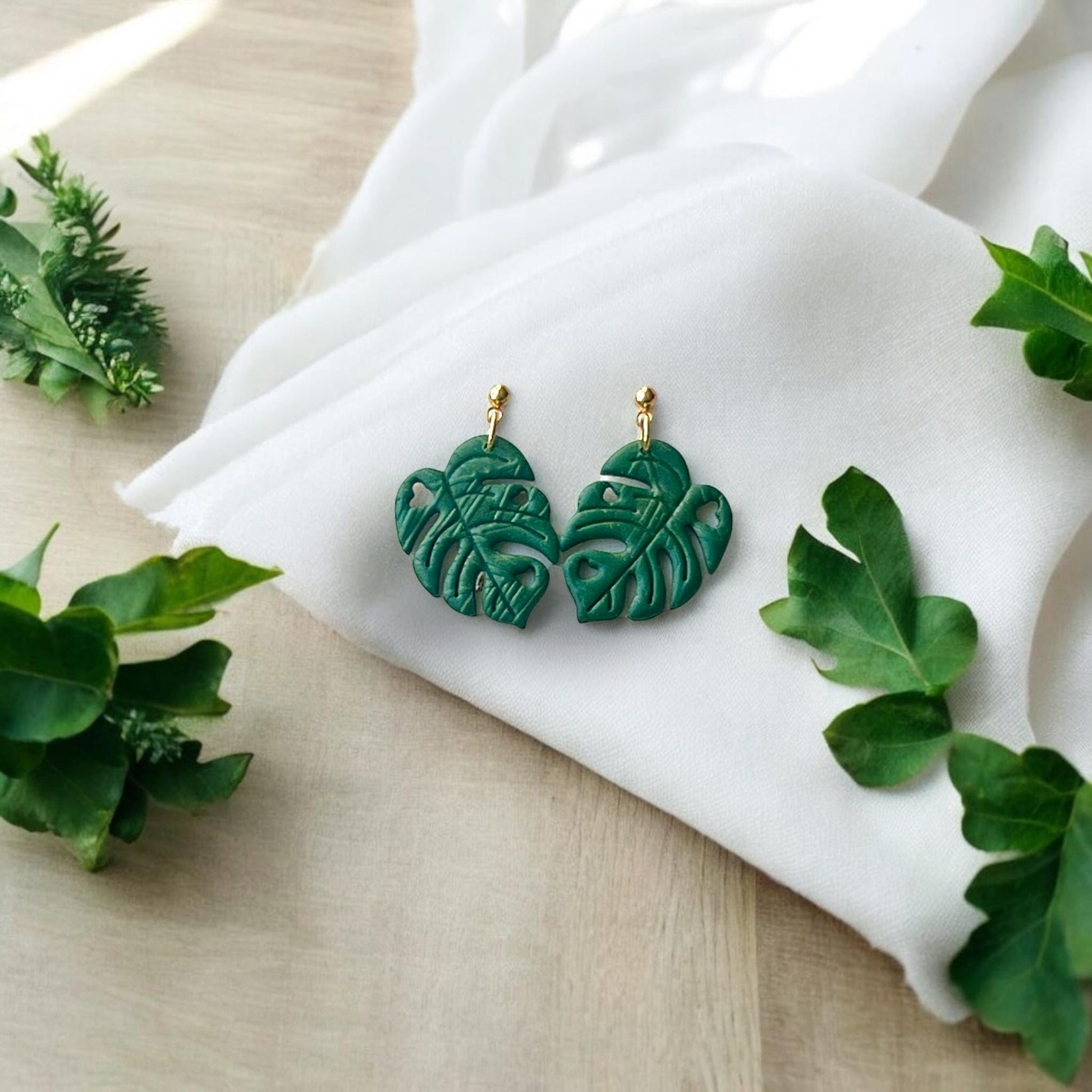 finished green earrings on fabric with leaves