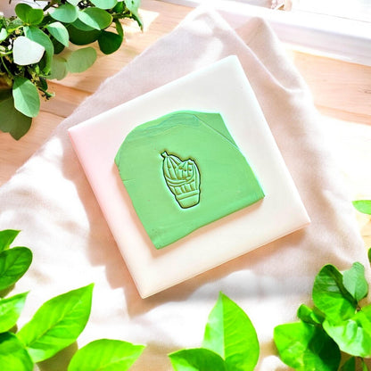 Green slab of polymer clay with a western cactus couple cutter impression on a white tile