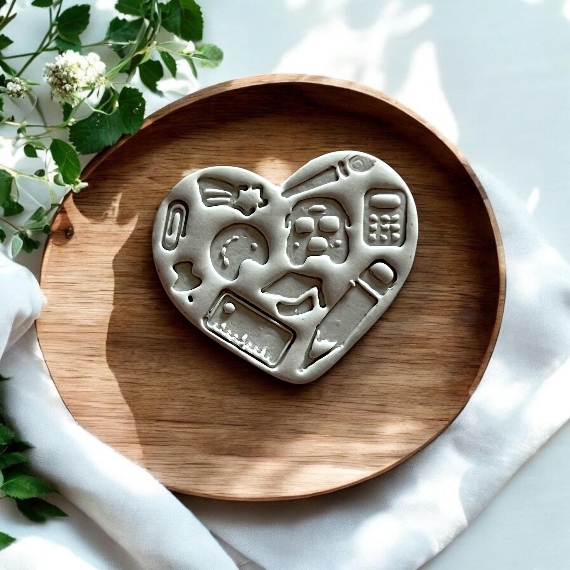 Finished polymer clay heart with school icons on wood tray, styled for product showcase