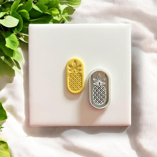 Pineapple clay earring next to matching cutter on white background