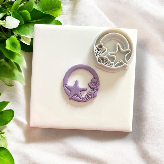 Finished seashell clay design next to matching cutter showing the cutout and embossed shapes clearly