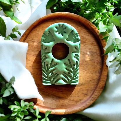 Finished green botanical arch piece styled on wood tray with greenery and sunlight