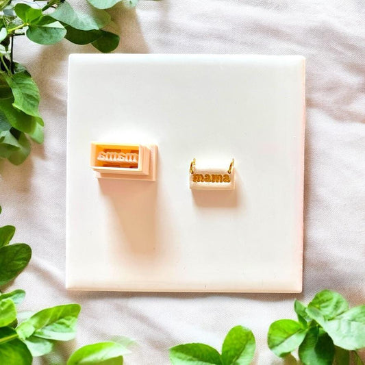 Golden &quot;mama&quot; charm displayed next to matching cutter on white background