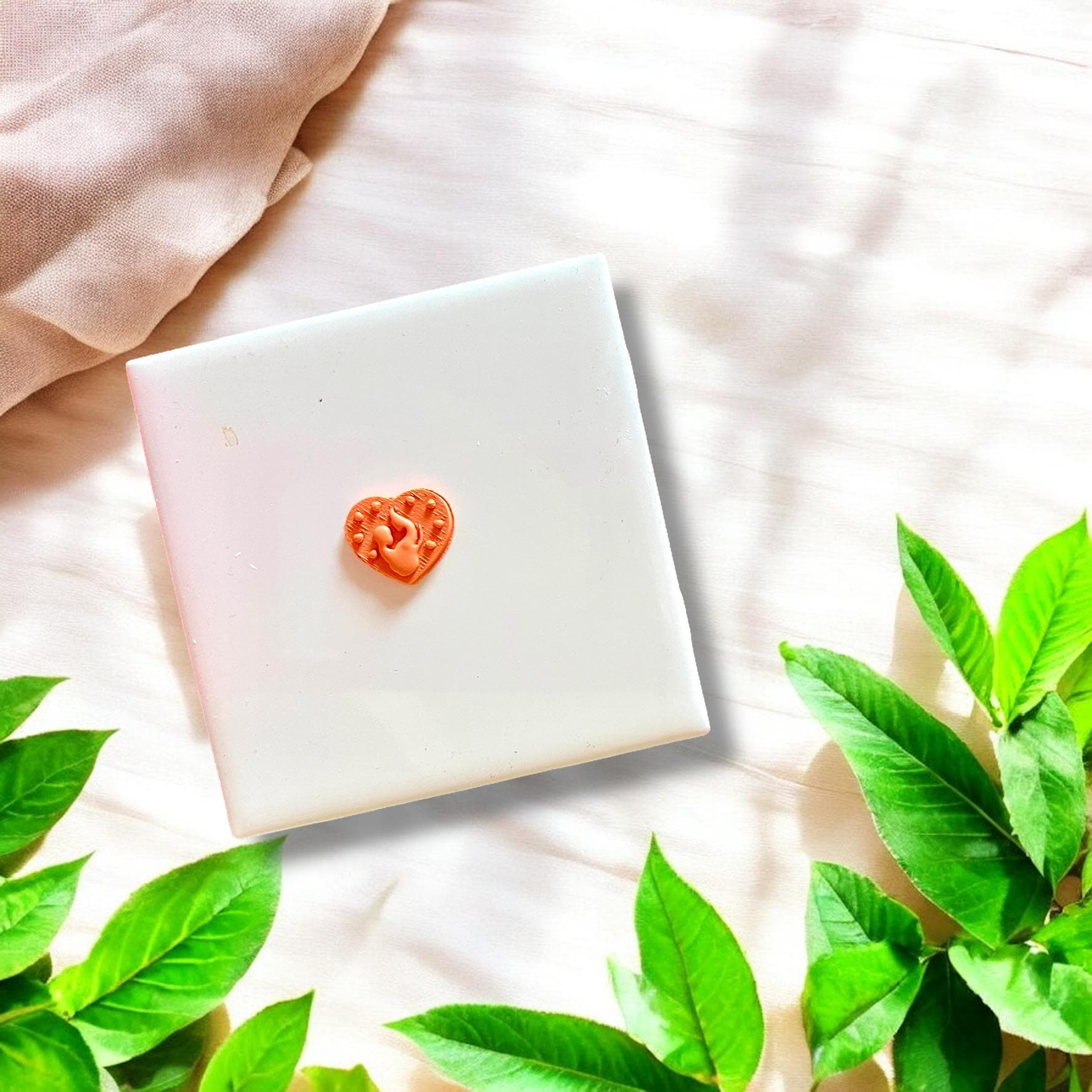 Small orange clay heart with mom and baby silhouette detail, displayed on a white background.