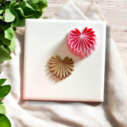 Palm leaf clay cutter next to a finished clay piece in leaf design