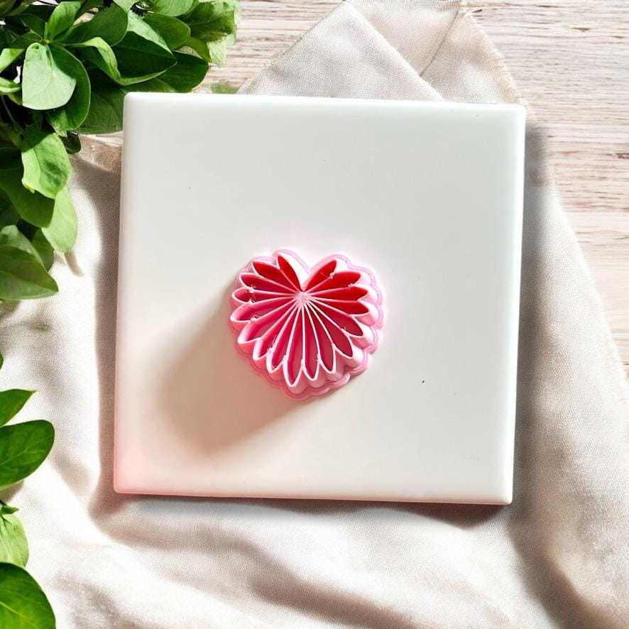 Top view of pink palm leaf polymer clay cutter shown on tile surface
