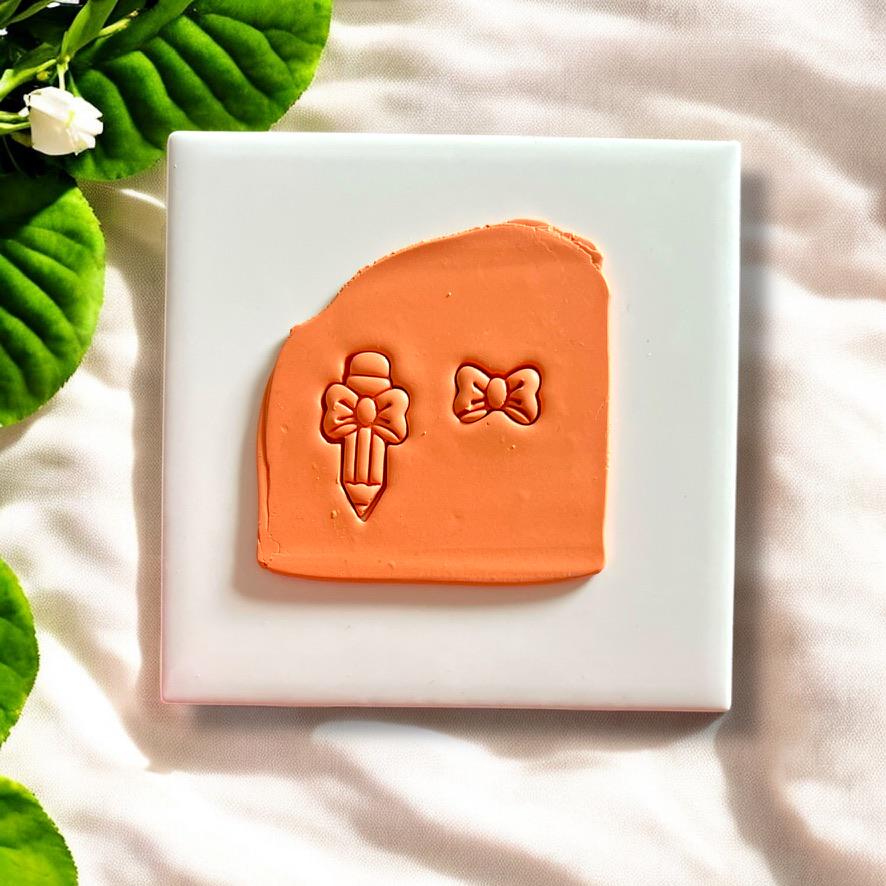 Polymer clay slab with detailed pencil and bow shape pressed using clay cutter, perfect for earring making