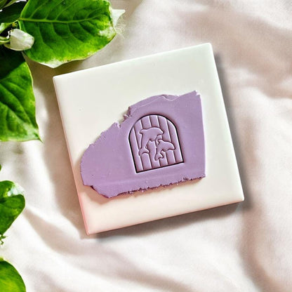Purple polymer clay with an embossed dolphin landscape in arch shape made using clay cutter
