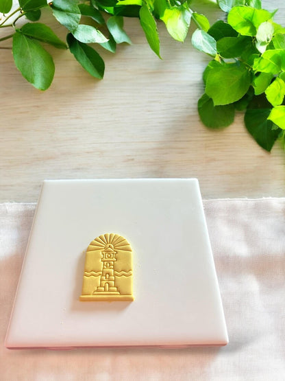 Finished clay piece showing a lighthouse within an arch, ideal for summer jewelry designs like pendants or drop earrings