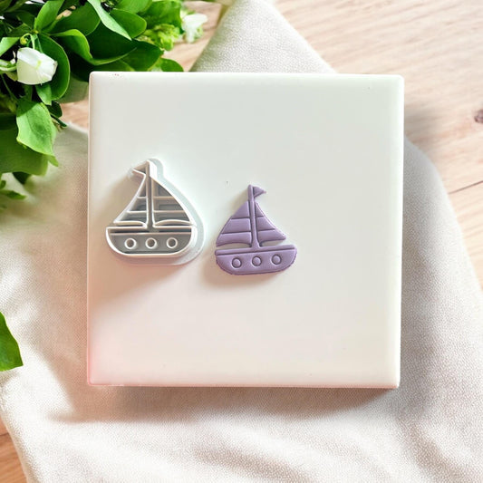 Polymer clay sailboat cutter alongside its lavender clay cutout, designed for nautical-themed jewelry.