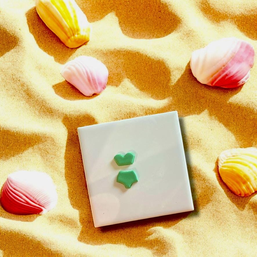 Bikini clay cutters displayed on beach sand with seashells, perfect for beach-inspired designs.