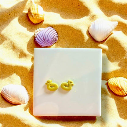 Finished clay earrings made with Duckie Pool Floatie cutter, displayed on white tile