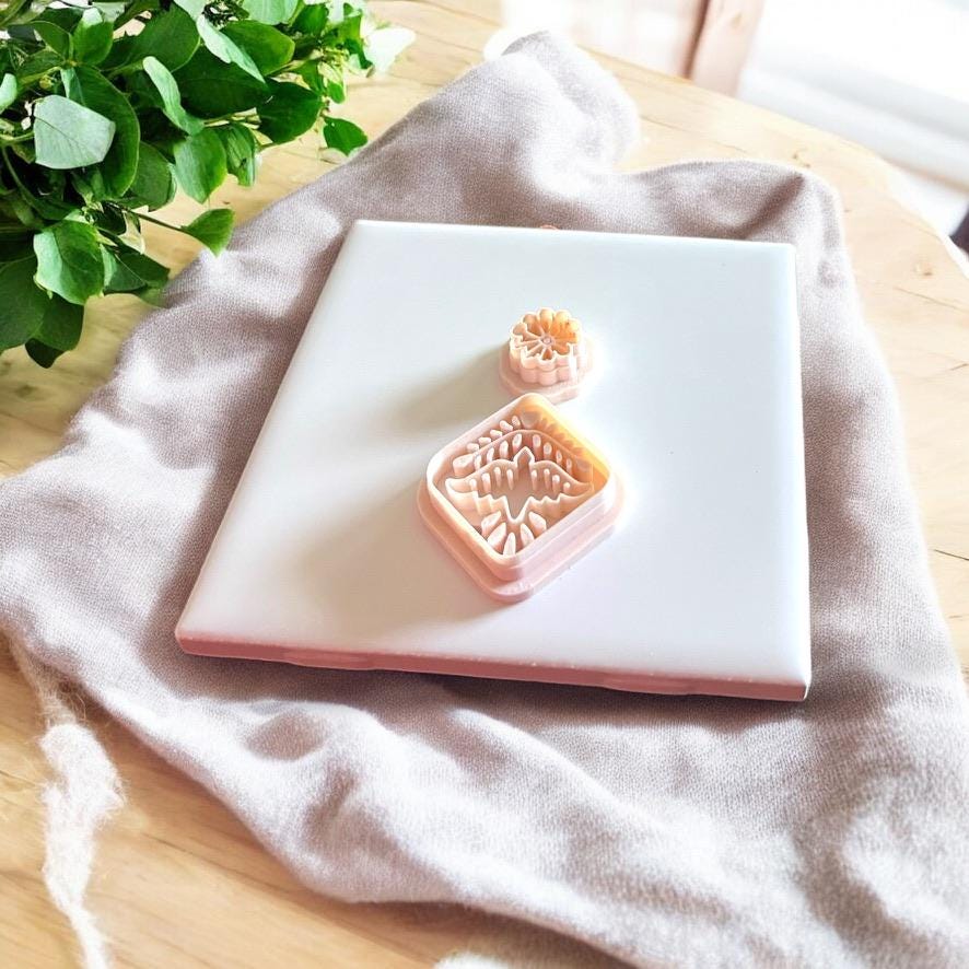 Full display of Aztec bird and flower clay cutters and impressions arranged on a white tile background