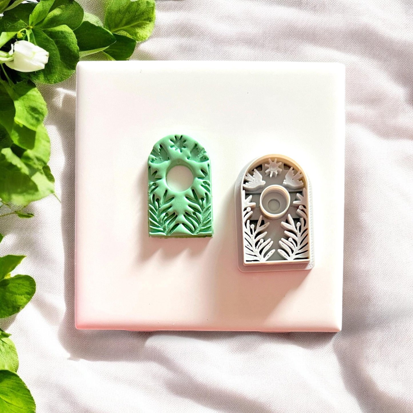 Boho arch clay piece beside its matching white cutter with detailed botanical pattern