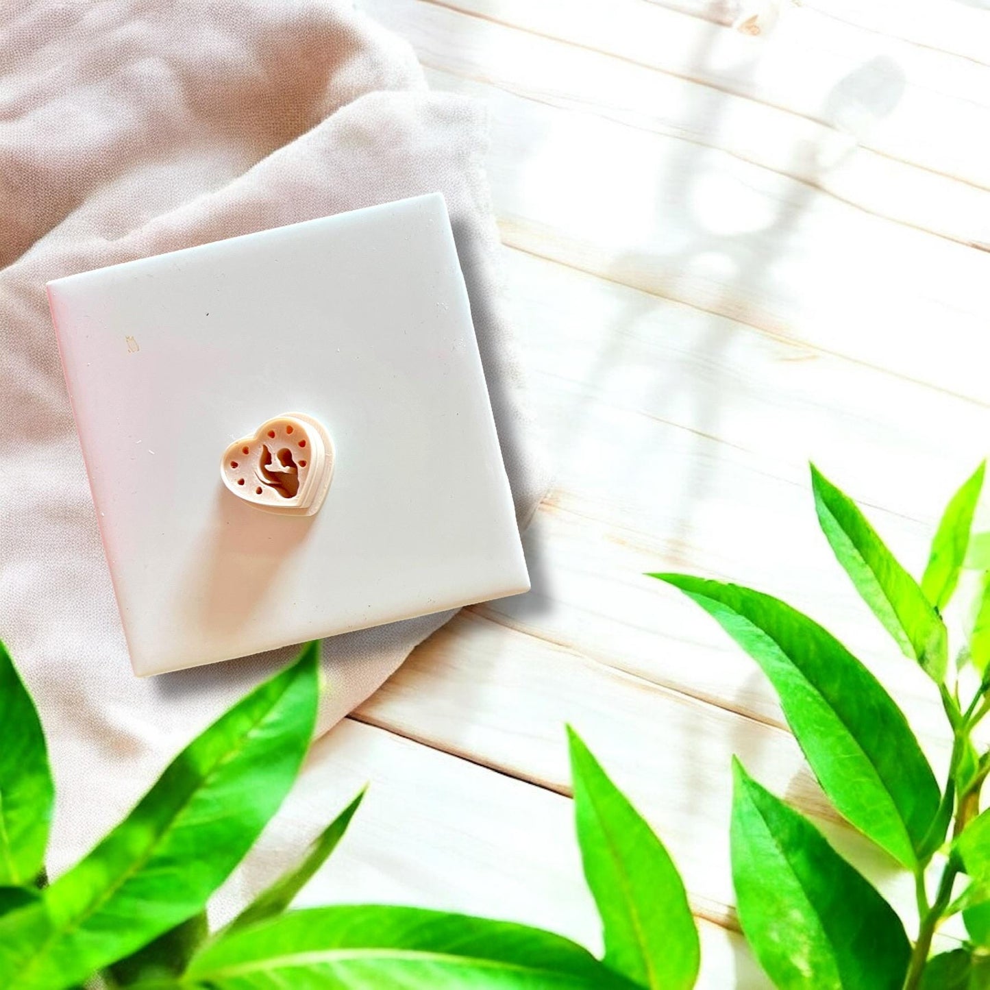 Mother and baby shaped white clay cutter resting on a white tile with soft natural shadows.