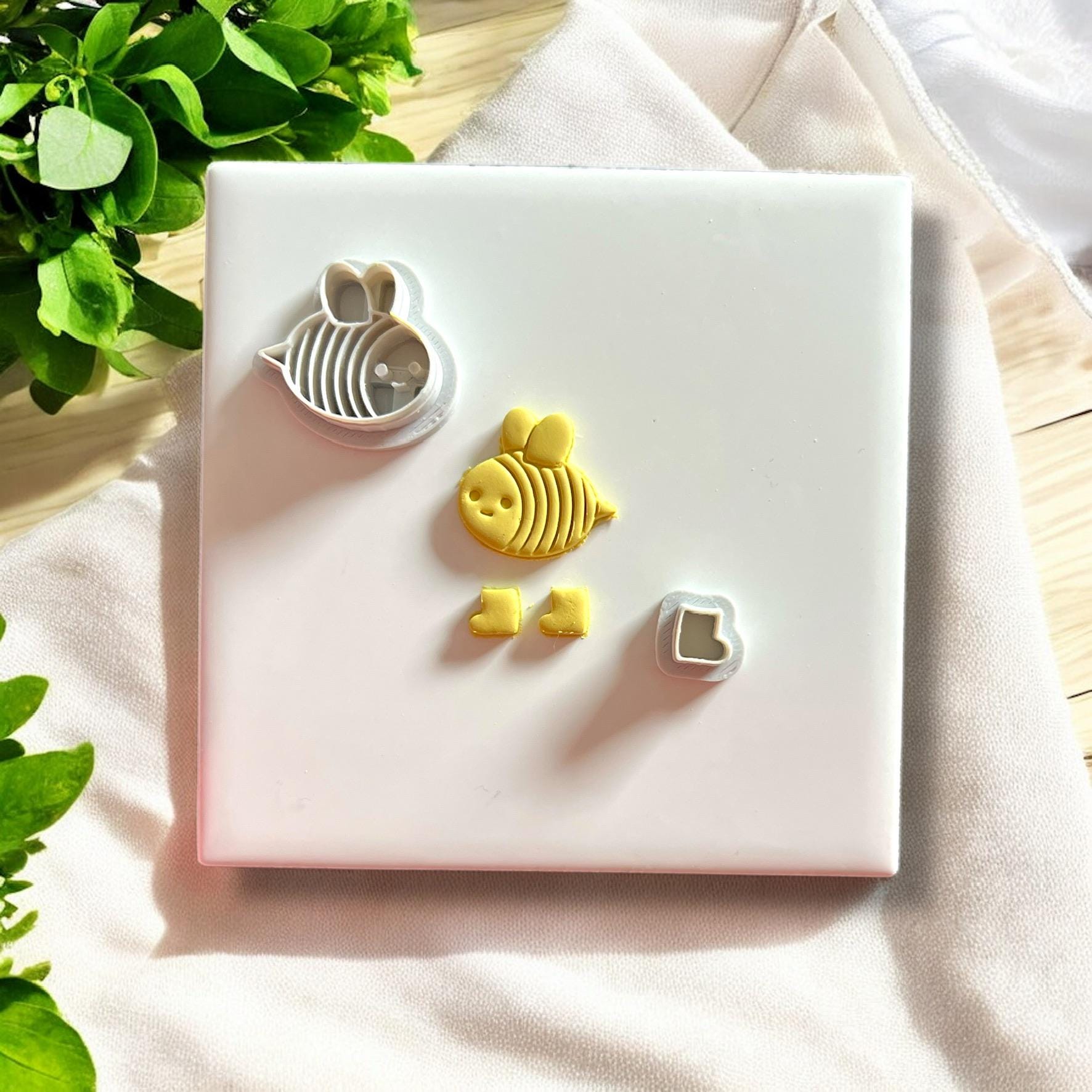 Polymer clay cutter and matching clay bee and boot pieces side by side showing tool and result clearly.