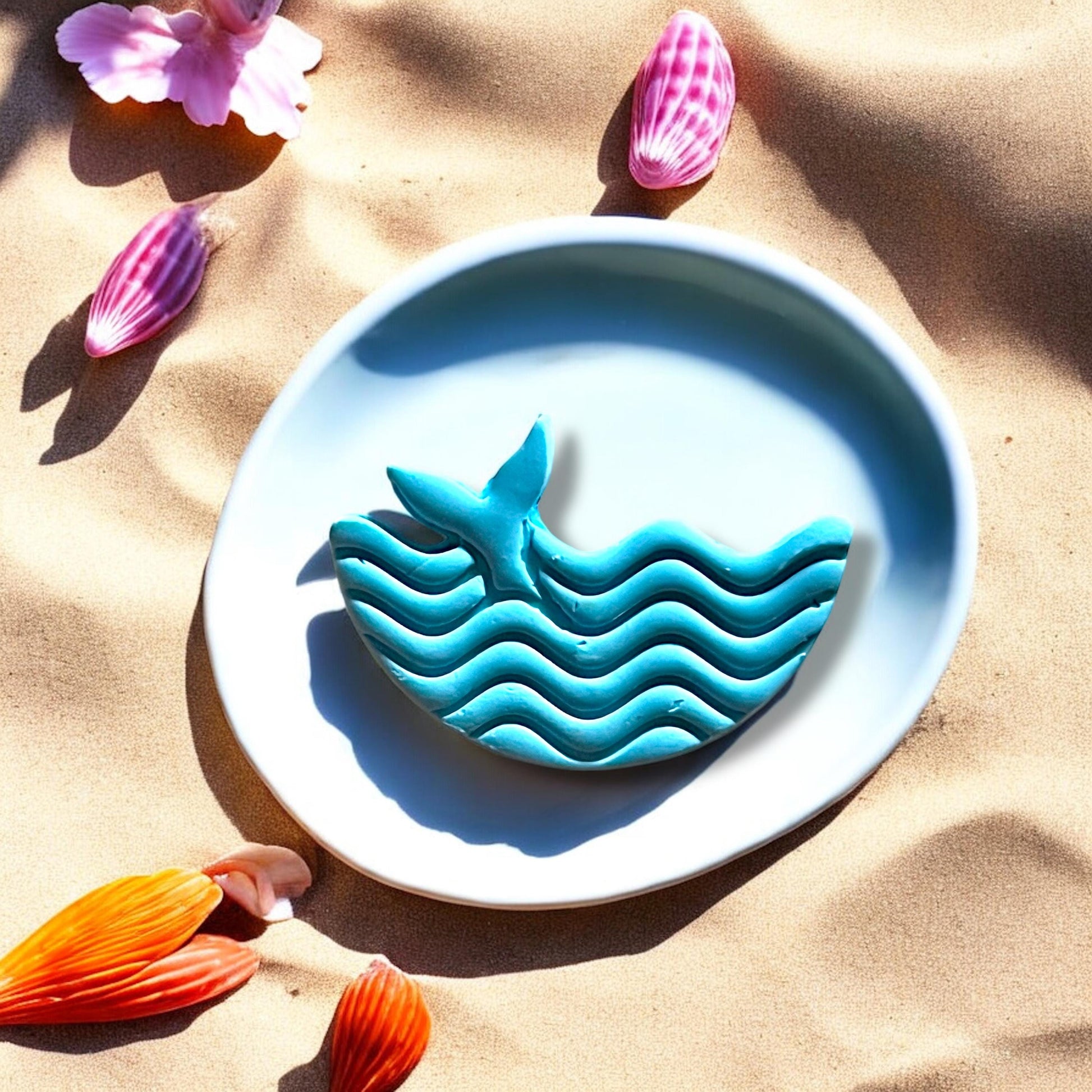 Finished blue whale clay piece shown in beach setting with shadow