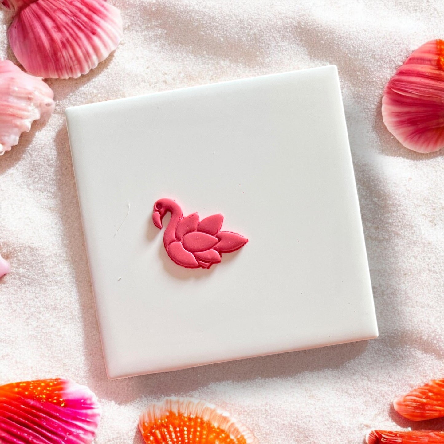 Completed pink flamingo clay piece with feather detail centered on tile