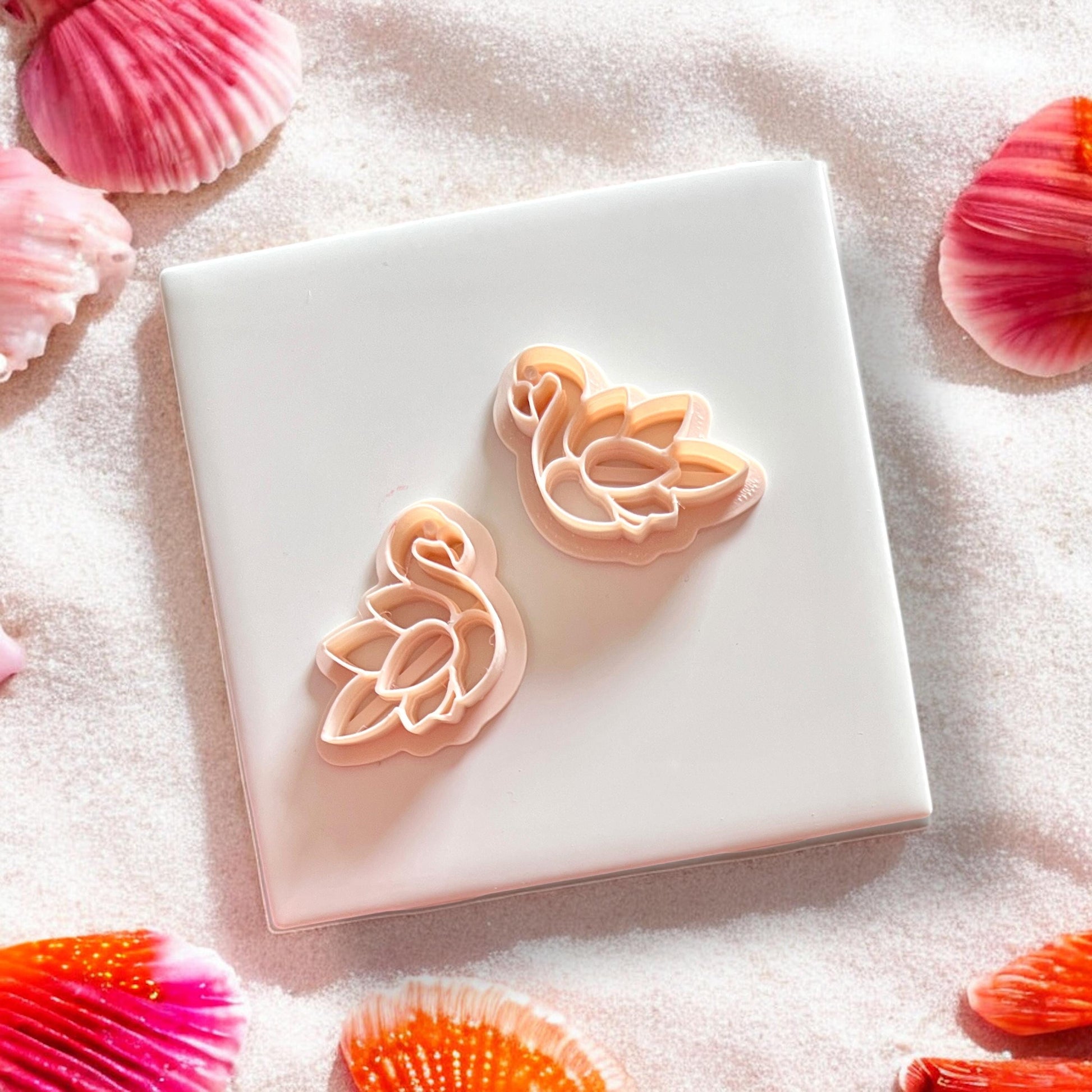 Two flamingo cutters with feather design displayed on white tile