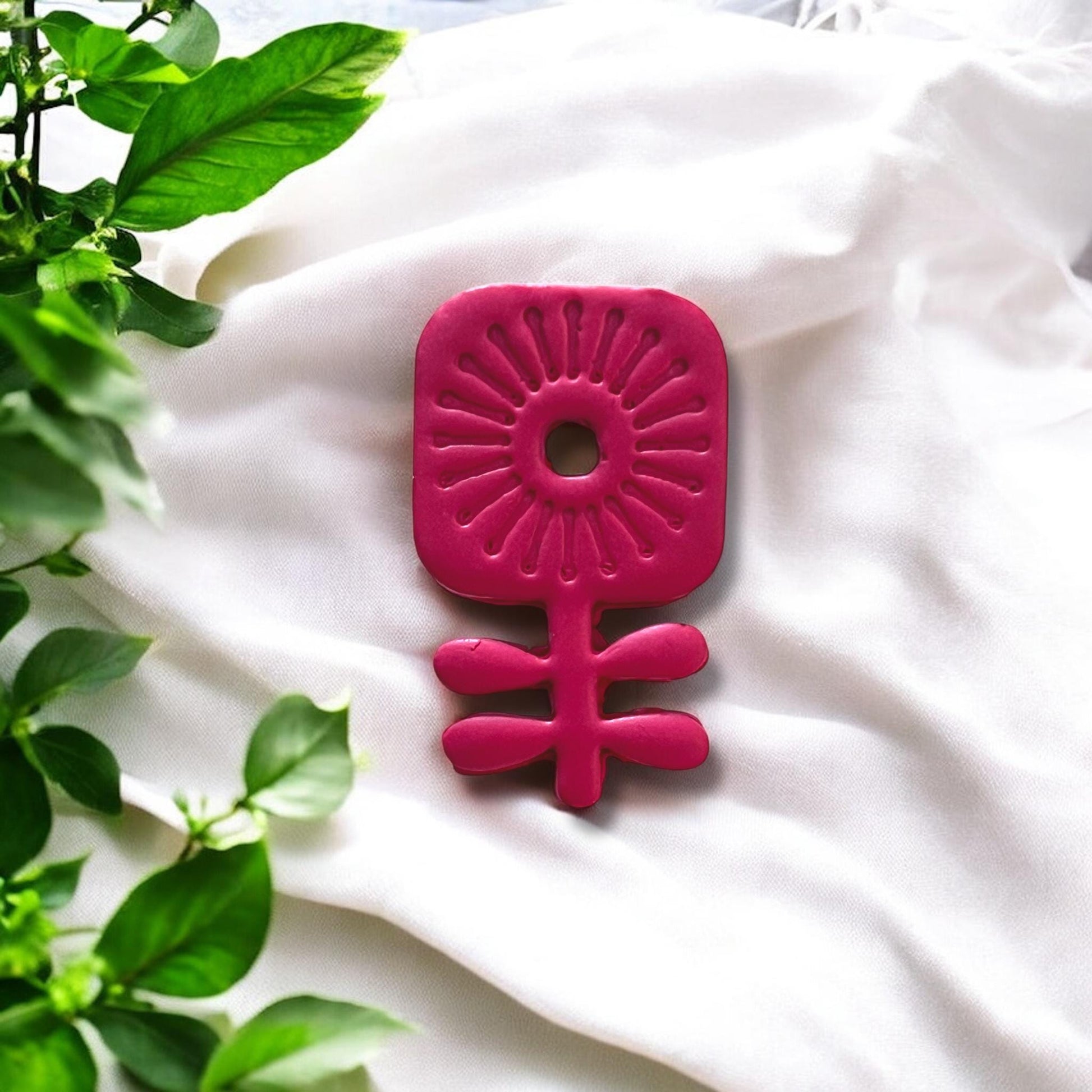 Large red clay flower cutout styled on white fabric backdrop