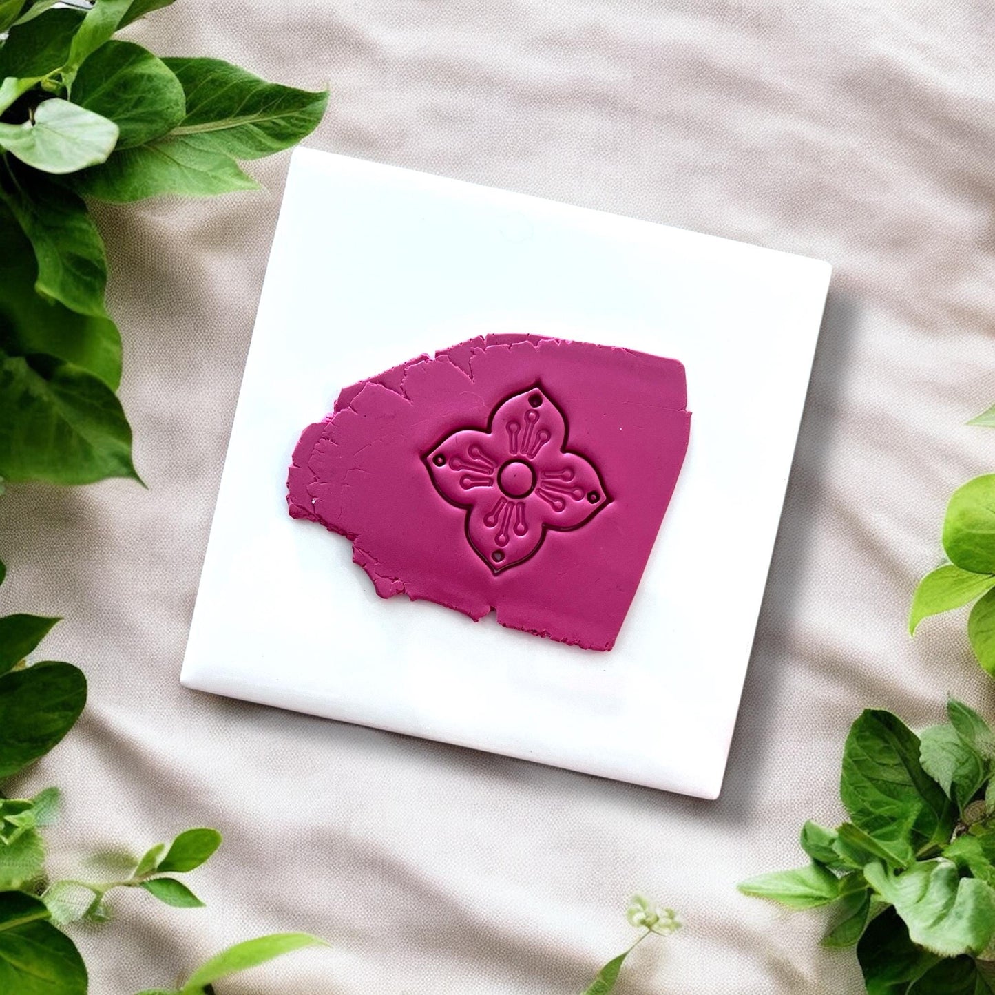 Pressed magenta clay slab showing floral cutter impression with petal lines and center circle