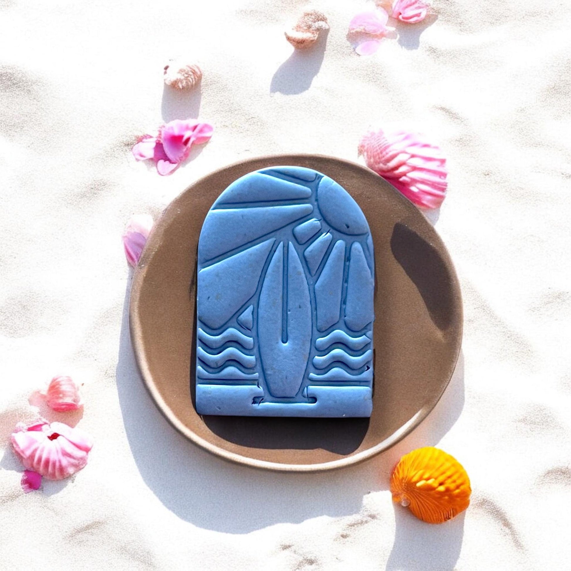 Blue surfboard scene clay cut on plate with shells and sand