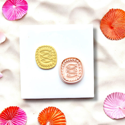 Pink oval fish trio clay cutter displayed on a white ceramic tile