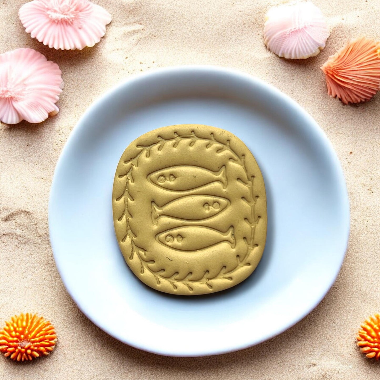 Yellow clay stamped with trio fish design on white tile and beach background