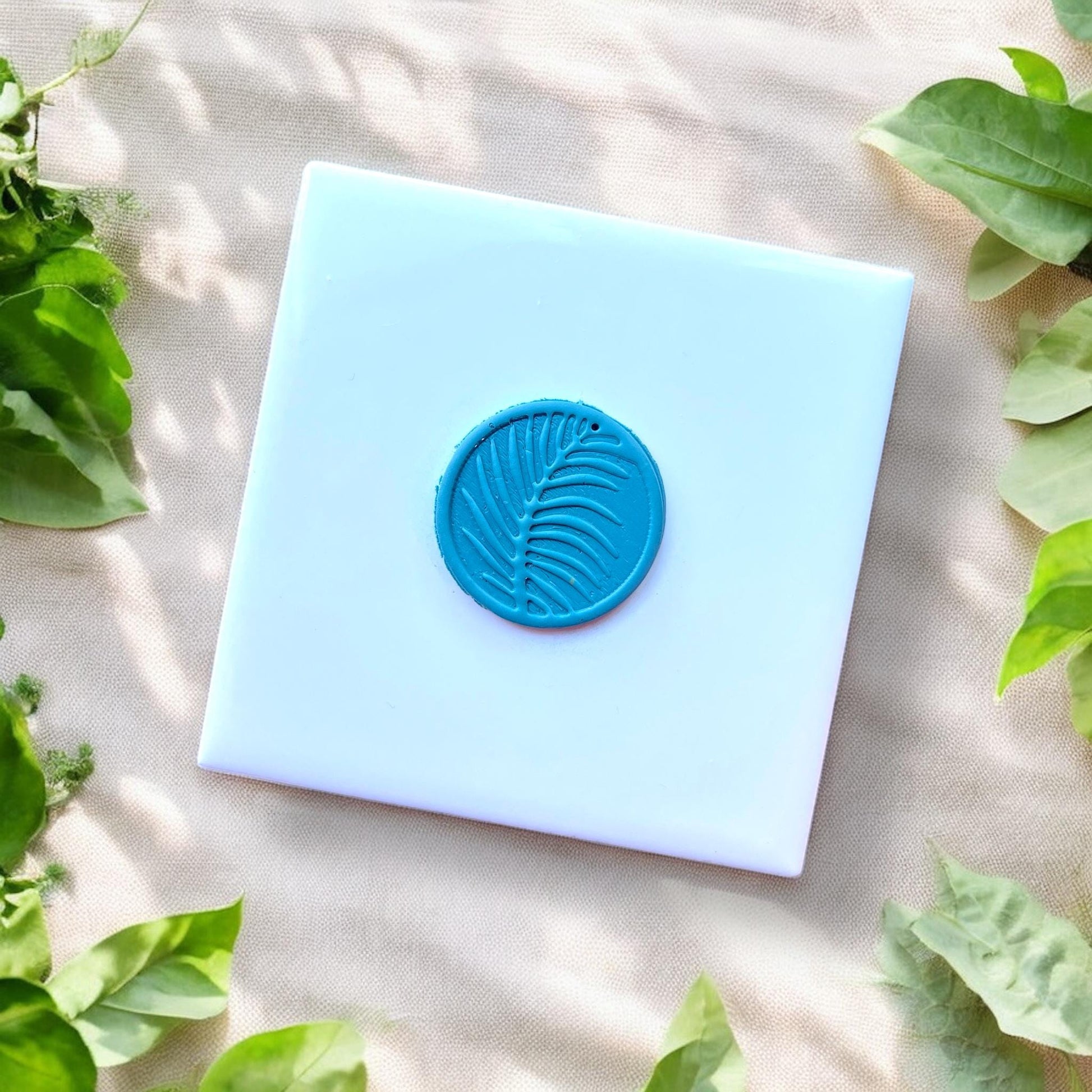 blue clay charm with tropical leaf