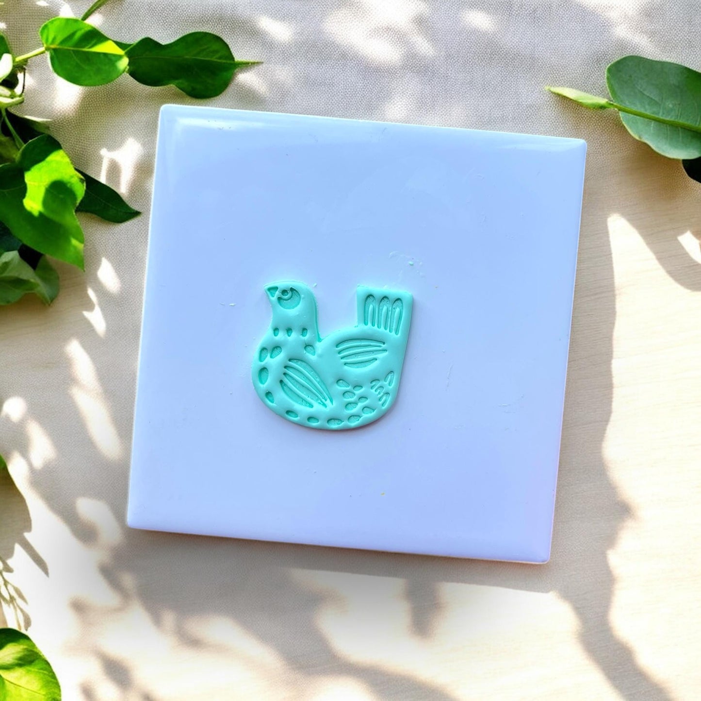 aqua bird-shaped clay charm with carved details