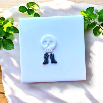 white skull charm and black bone boots on white tile