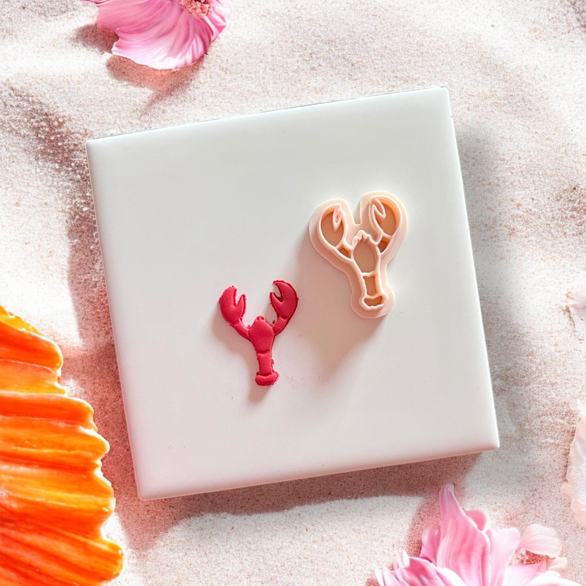 Lobster earring cutter next to pink cut clay piece