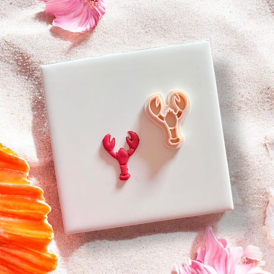 Lobster earring cutter next to pink cut clay piece
