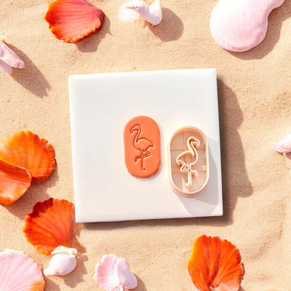 Flamingo clay shape and matching cutter shown side-by-side on a white tile, seashells scattered around