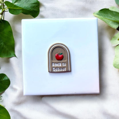 Finished clay earring with painted apple and white text