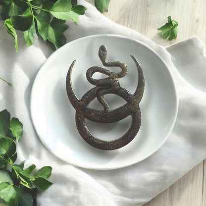 Final black pendant styled on plate with white cloth and greenery