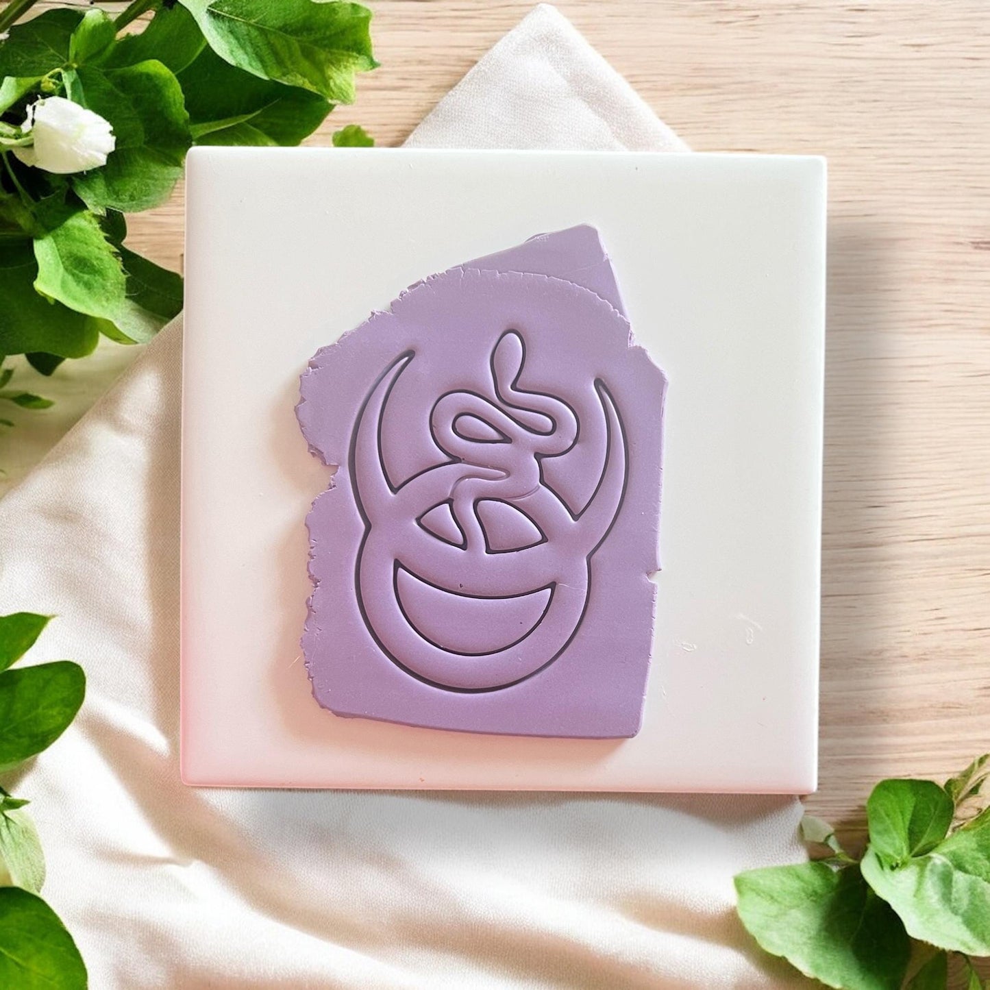 Purple clay slab with snake and crescent pendant impression