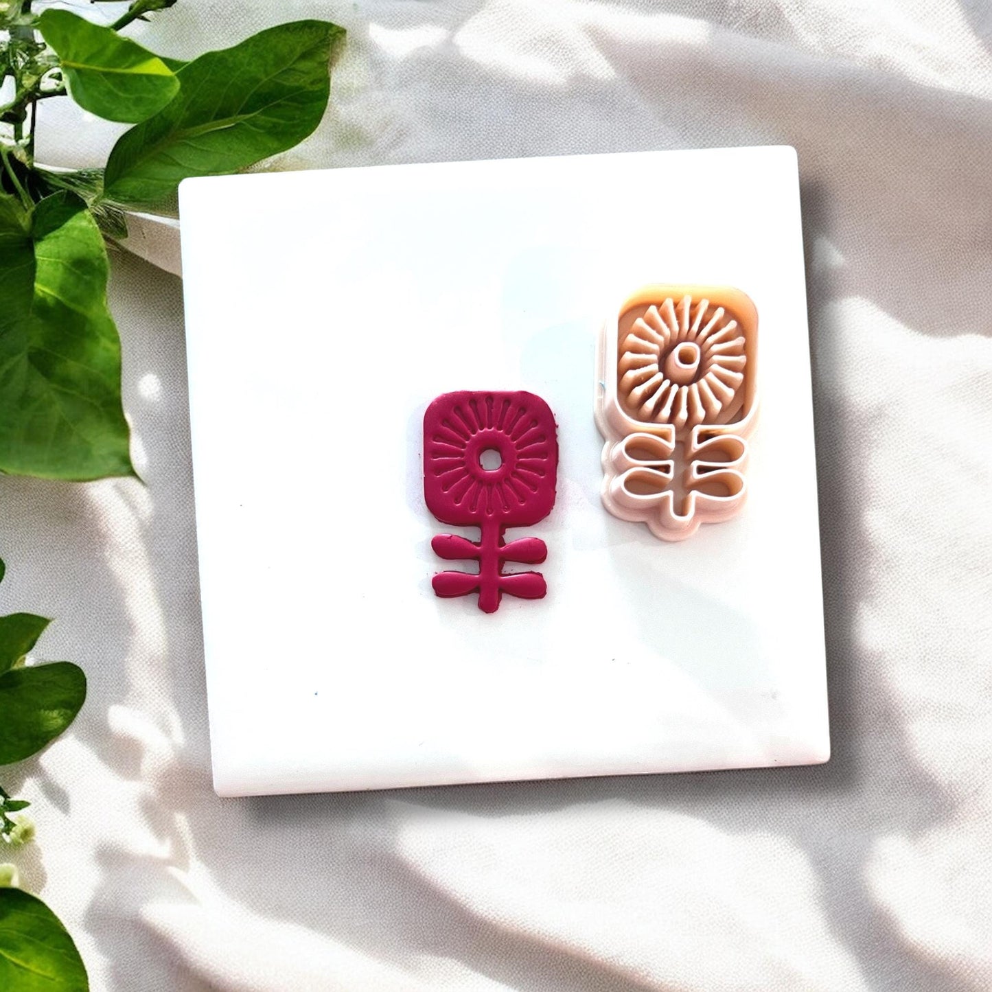 Clay flower next to matching plastic cutter on white background