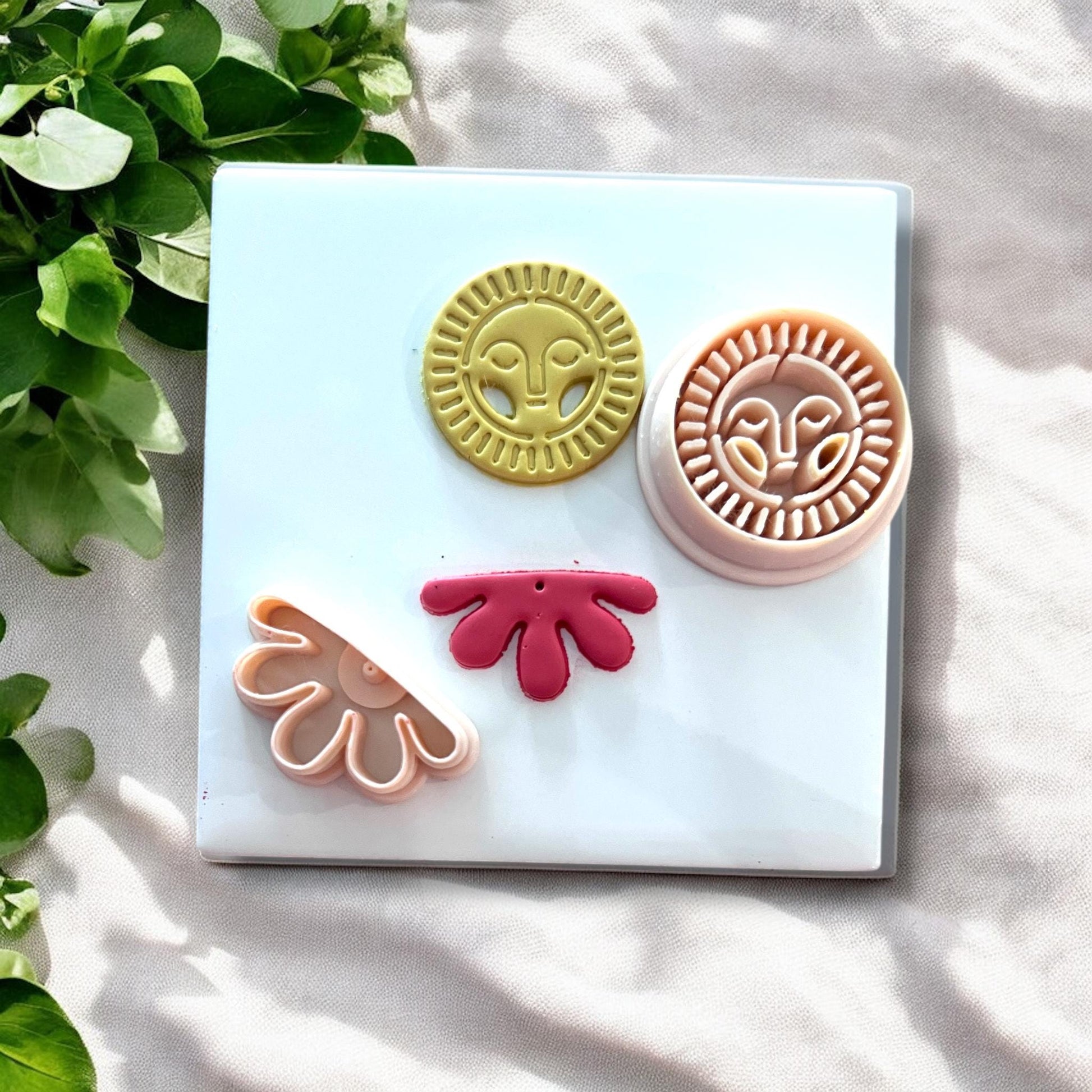 Yellow sun face topper paired with a red abstract flower clay drop