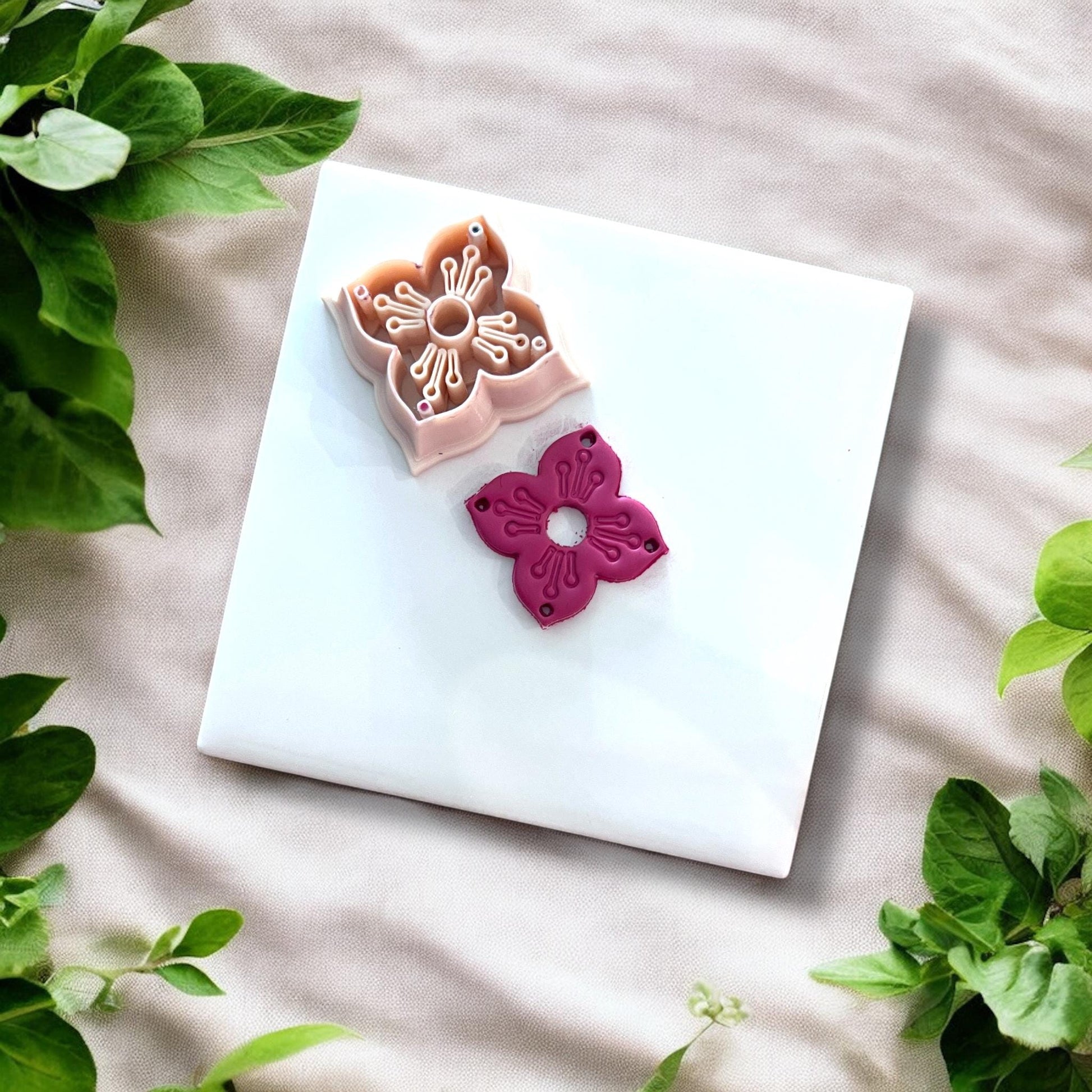 Cutter and finished clay flower piece side by side on a tile surface