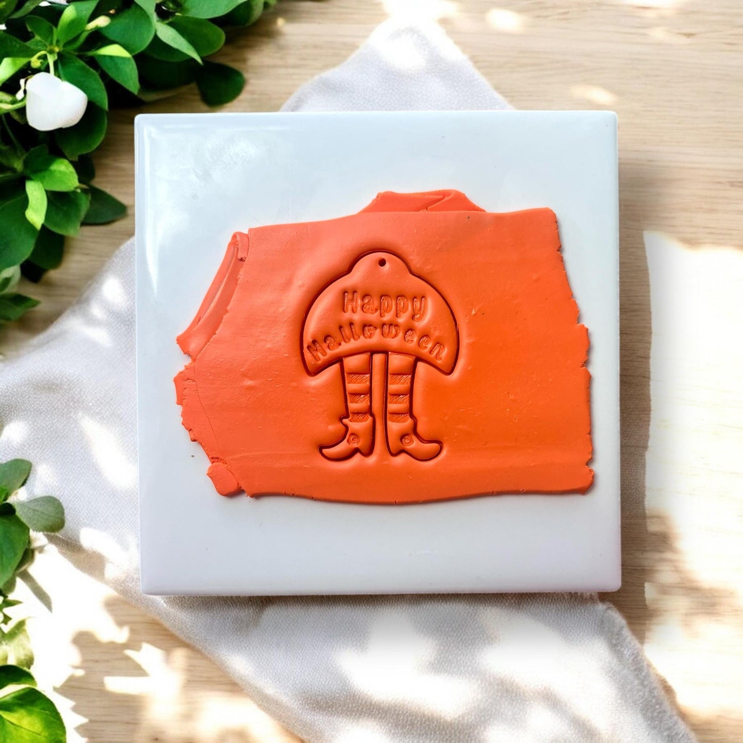 Orange slab with witch legs and “Happy Halloween” clay impression