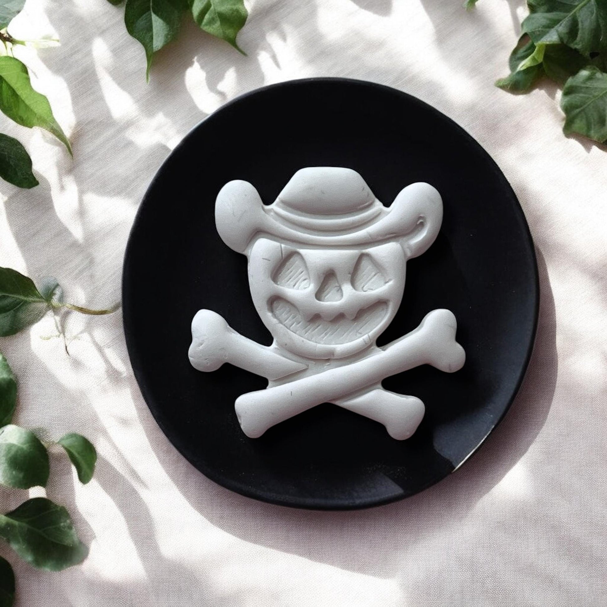 Halloween cowboy skull clay piece on black plate with greenery