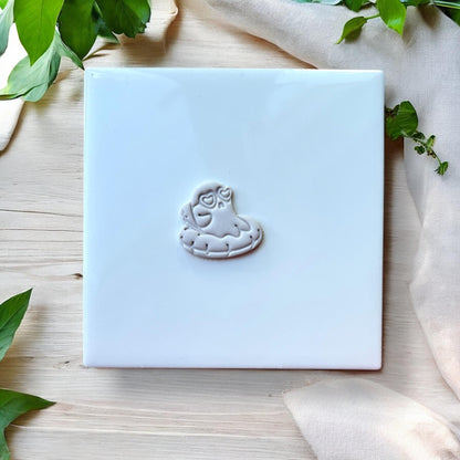 Close-up of grey clay ghost on floatie earring imprint