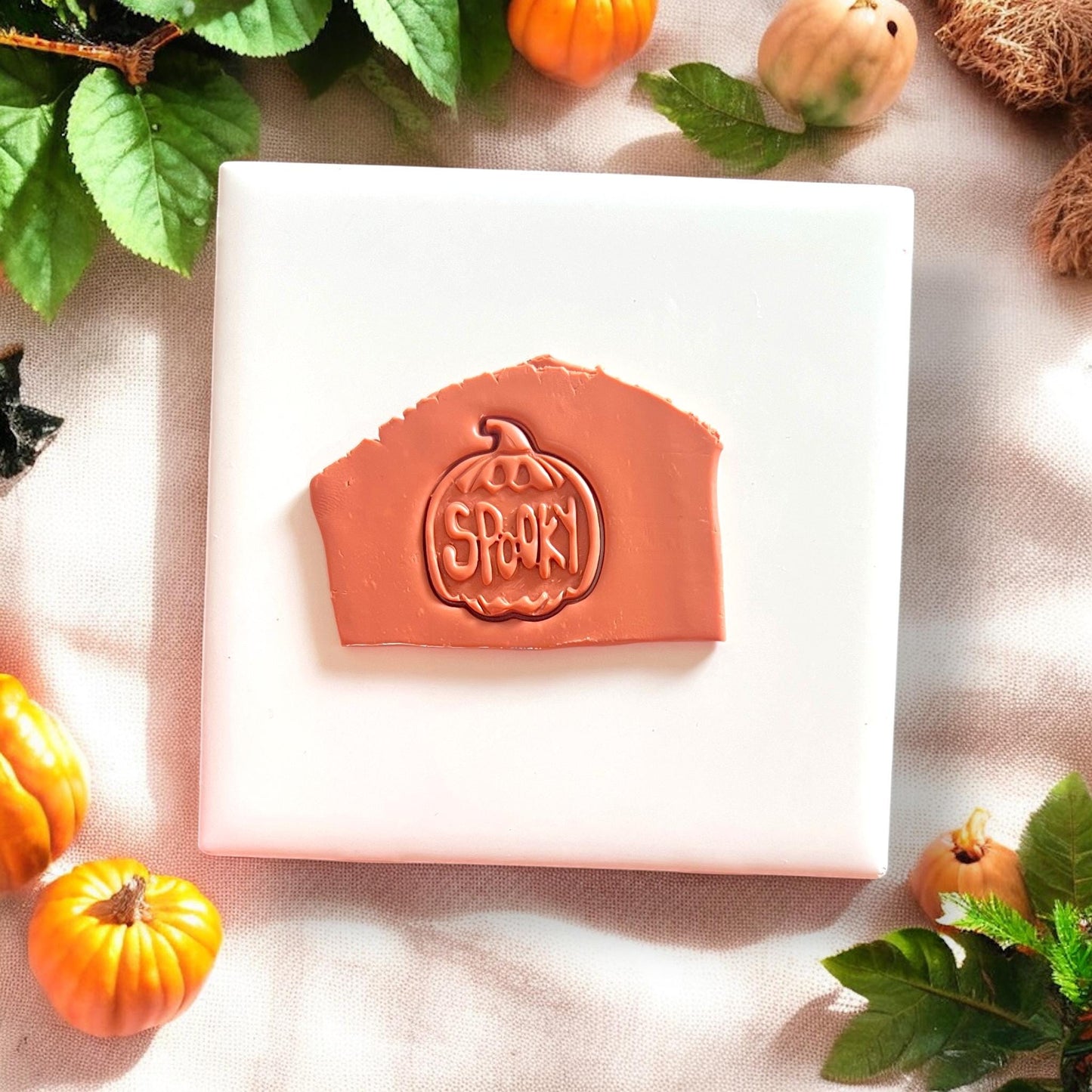 Pumpkin clay cutter with &quot;Spooky&quot; text impressed in terracotta clay