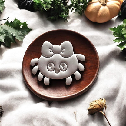 Clay spider with bow on round wooden plate