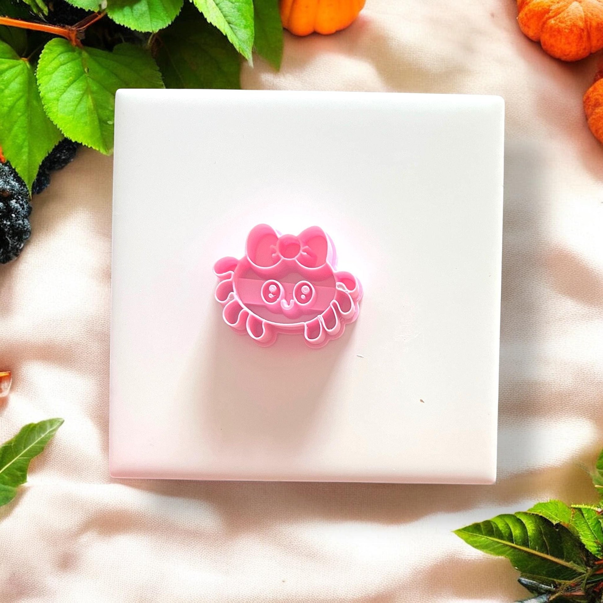 Pink girly spider polymer clay cutter on white tile