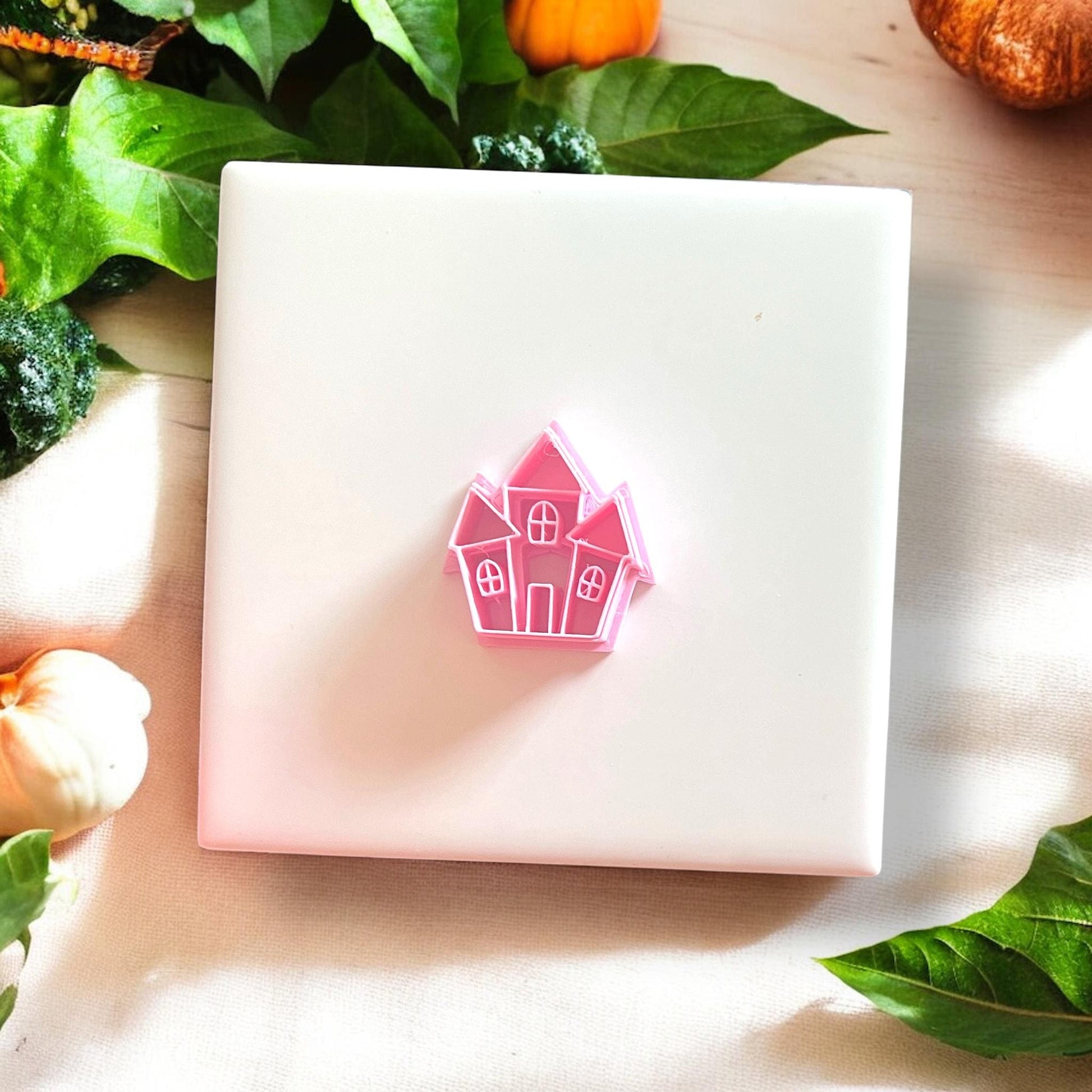 Pink plastic haunted house cutter displayed on white tile