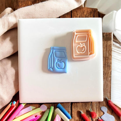 lunch bag and apple clay impression with matching cutter on white tile